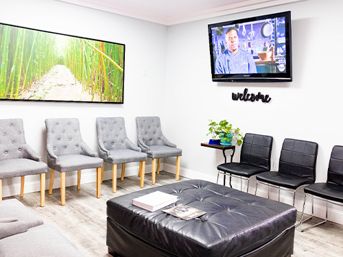 Modern orthodontic waiting room with gray chairs, TV screen, and comfortable seating area.