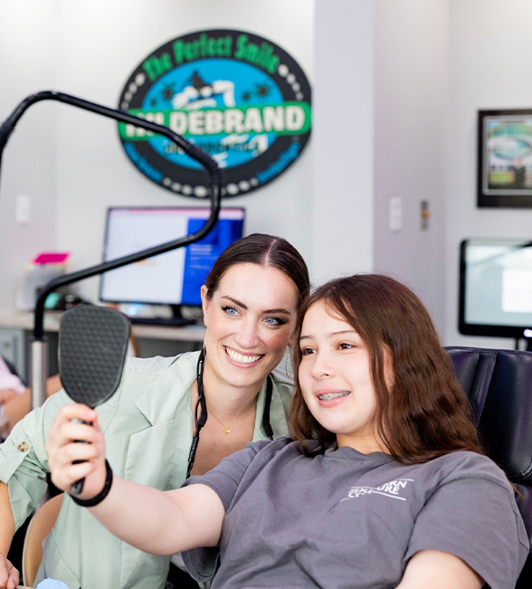 Two women smiling at microphone in Hildebrand Orthodontics office studio setting.