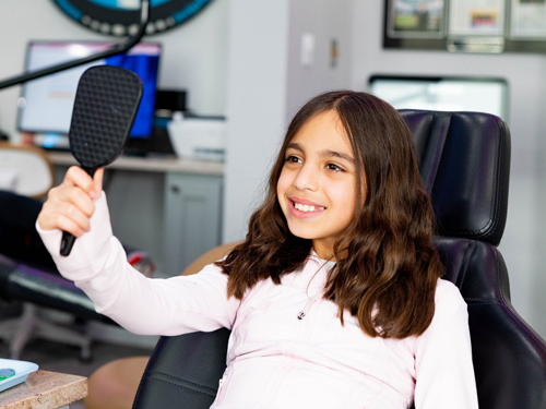 Young woman in white shirt holding microphone in orthodontic office setting.