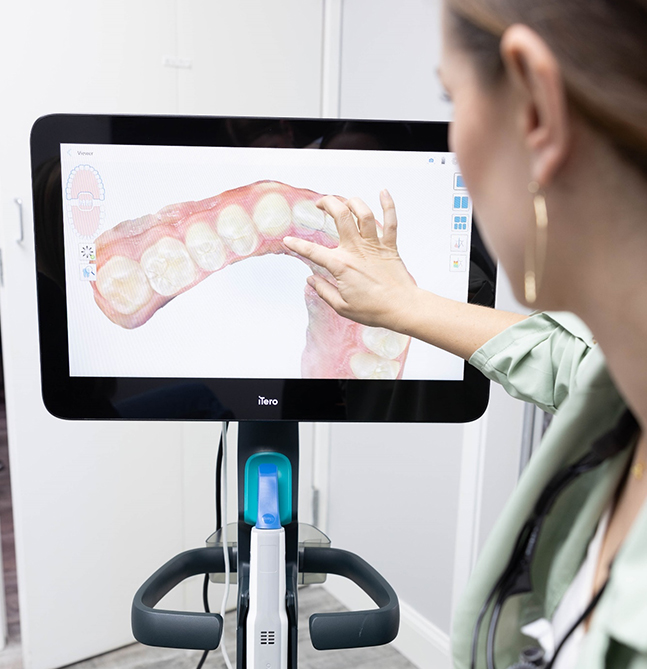 Woman examines digital orthodontic model of teeth on dental display screen